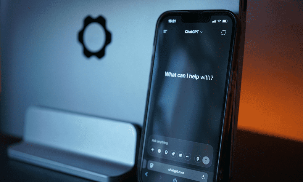 A cell phone screen shows the standard welcome from ChatGPT, "What can I help with?" to elucidate the importance of maintaining brand integrity through AI agents that act as an extension of the company when interacting with potential customers. 
