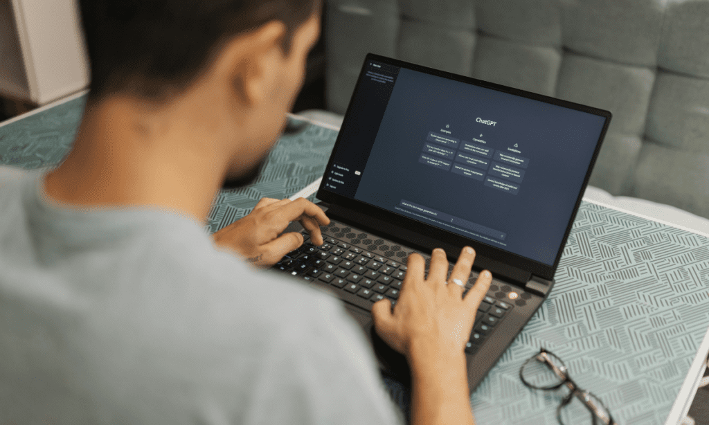 A man prepares to type a query into ChatGPT on a laptop, highlighting the change in SEO from an emphasis on keyword research to one on prompt research for AEO. 