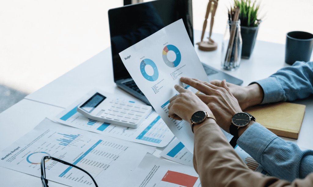 Two individuals point to a chart on a piece of paper in an office setting, demonstrating the previous avenues of conversion tracking that are not longer applicable in the age of AI in digital marketing. 