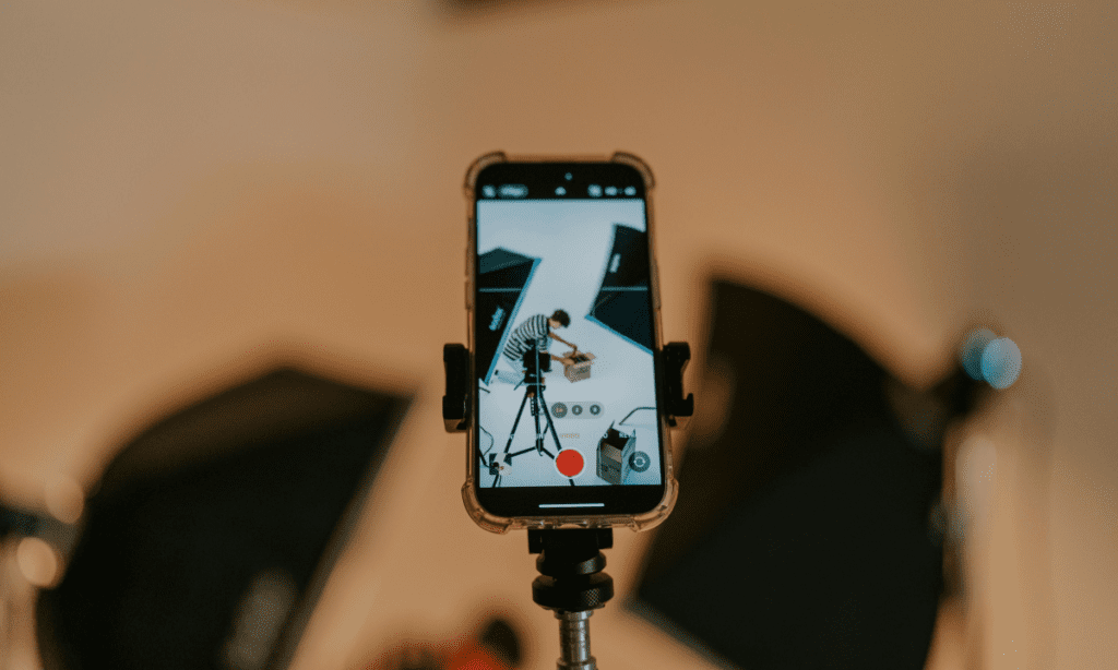 A smart phone screen shows a small product brand business owner shooting content for social media ads, showcasing the time and effort required to make social media ads that drive sales in 2026. 
